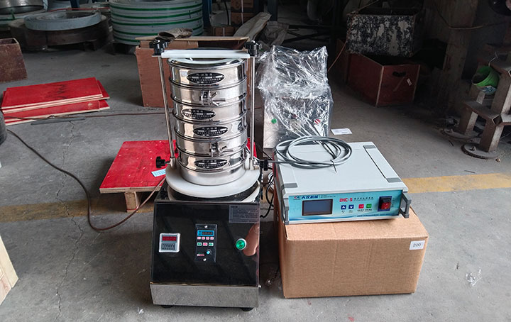 Ultrasonic test sieve shaker with stacked test sieves and ultrasonic power supply for fine powder particle size analysis.